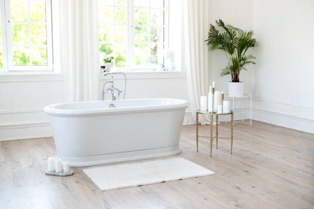 istock White modern bathroom with silver fittings with large sunny windows, decorations and plants. Interior design concept. Soft selective focus. 1403040178