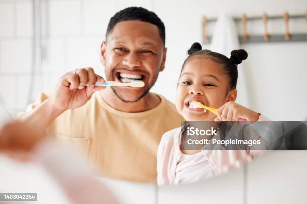 Happy Mixed Race Father And Daughter Brushing Their Teeth Together In A Bathroom At Home Single African American Parent Teaching His Daughter To Protect Her Teeth Stock Photo - Download Image Now