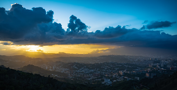 Views to the west of the city of Caracas along with a beautiful sunset that dyes the sky with orange yellow and blue tones