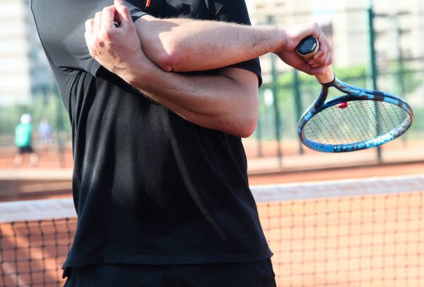 istock Man holding elbow in pain while playing tennis 1403042831