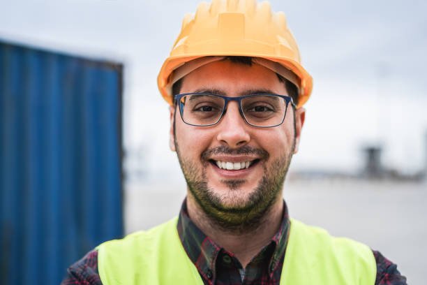 istock Happy young man smiling on camera working at freight terminal port on background - Focus on face 1403043782