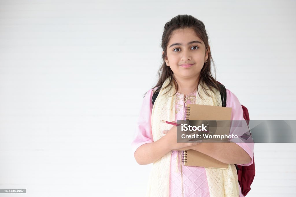 cute Indian girl smiling and writing on notebook for learning, education concept Middle Eastern Ethnicity Stock Photo