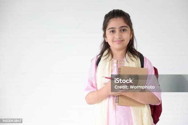 Cute Indian Girl Smiling And Writing On Notebook For Learning Education Concept Stock Photo - Download Image Now