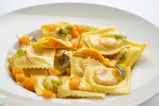 Cooked ravioli with pumpkin and Parmesan on a white plate close up