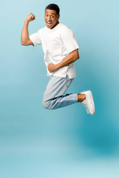 istock Excited overjoyed African-American young guy jump up on blue background, having fun in studio 1403045855