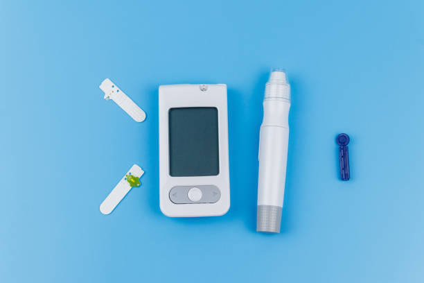 istock Digital glucometer, lancet pen, disposable needles and test strips on pastel blue background. Top view. Diabetes concept 1403045994