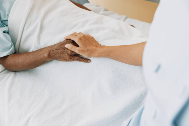 istock Nurse with patient in bed, holding hands. 1403047321