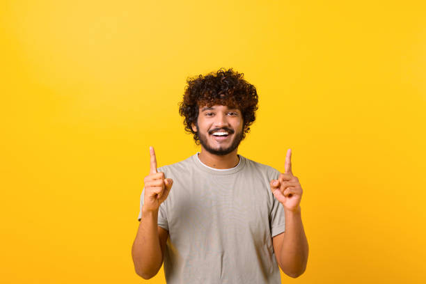 istock Attractive Indian man with happy facial expression pointing up with both fingers, presenting copy space 1403048572