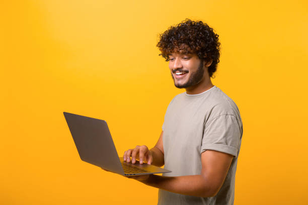 istock Smiling positive man holding laptop in hands and typing 1403048639