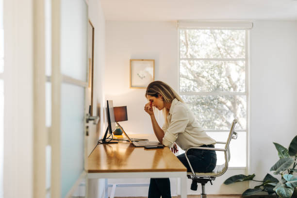 femme d’affaires épuisée ayant mal à la tête dans son bureau - stress photos et images de collection