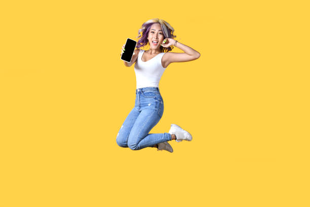 istock Asian woman holding smartphone with empty screen and jumping up. 1403049983