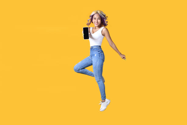 istock Asian woman holding smartphone with empty screen and jumping up. 1403050008