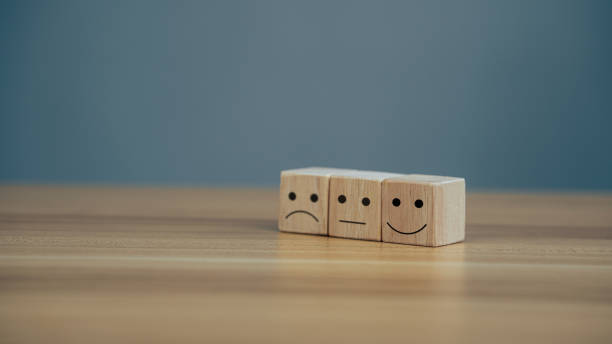 Close up icon smiley face and blurred sad face on wood cube. stock photo