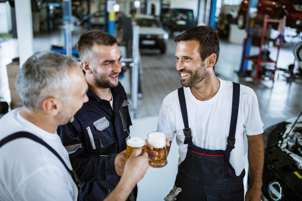 istock Happy auto mechanics toasting with beer on a break in a workshop. 1403051830