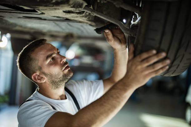 giovane meccanico che esamina le pause dell'auto in un'officina. - maintenance engineer car lamp protective workwear foto e immagini stock