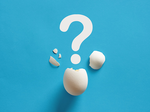 Cracked white chicken egg shell with question mark symbol. Surprise, mystery, uncertainty or baby gender prediction concepts.