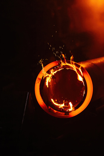 A orange hot steel slab casting on machine in factory.