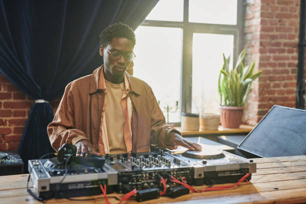 istock Young serious black man looking at dj board while touching turntables 1403054828