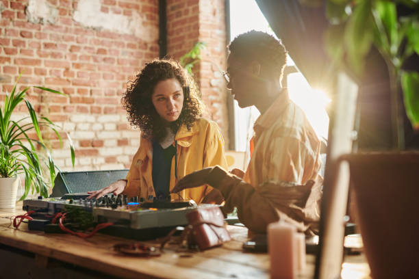 istock Young woman looking at black man explaining her how to create new music 1403054877