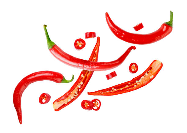 istock Chili pepper cut into pieces flies on a white. Isolated 1403056412