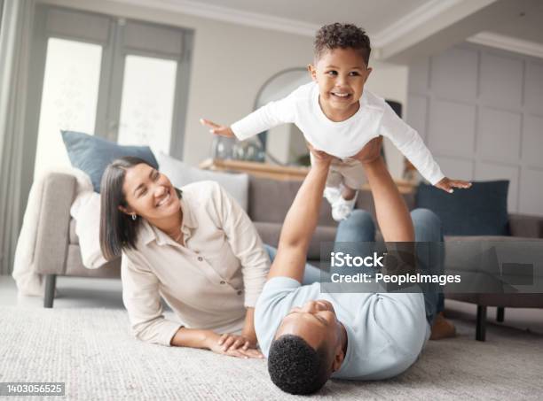 A Happy Mixed Race Family Of Three Relaxing On The Lounge Floor And Being Playful Together Loving Black Family Bonding With Their Son While Playing Fun Games On The Carpet At Home Stock Photo - Download Image Now