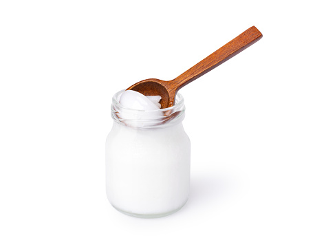 Coconut oil butter in glass jar with wooden spoon isolated on white background. Clipping path.