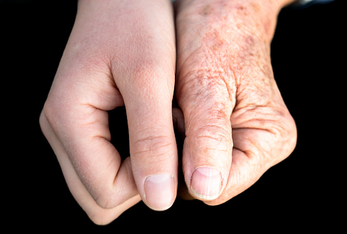 Two generations of women's hands held together - one in her twenties, and the other in her seventies.
