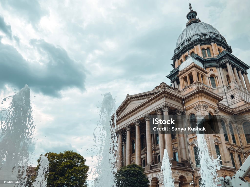 Water Fountain Sprays and Splashes in Front of the Illinois State Capitol Building. Ornamental water fountain on the grounds of the Illinois State Capitol Complex in Springfield, IL, USA. The majestic Illinois State Capitol Building stands tall in the background. Springfield - Illinois Stock Photo