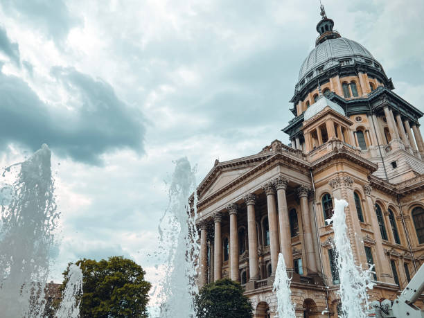 water fountain sprays and splashes in front of the illinois state capitol building. - old crane blue sky imagens e fotografias de stock
