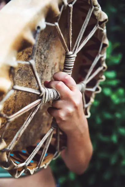 Detail of a person holding a shamanic drum. You can see the taut strings on the back.