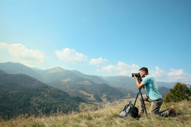 istock Professional photographer taking picture with modern camera in mountains. Space for text 1403063806