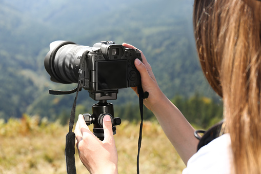 Woman taking photo of nature with modern camera on stand outdoors