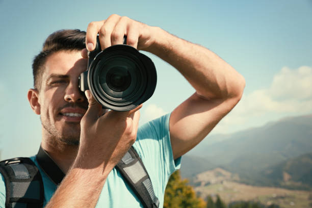 istock Professional photographer taking picture with modern camera in mountains, focus on lens 1403064013