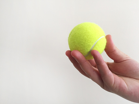 Female hand holding tennis ball with copy space