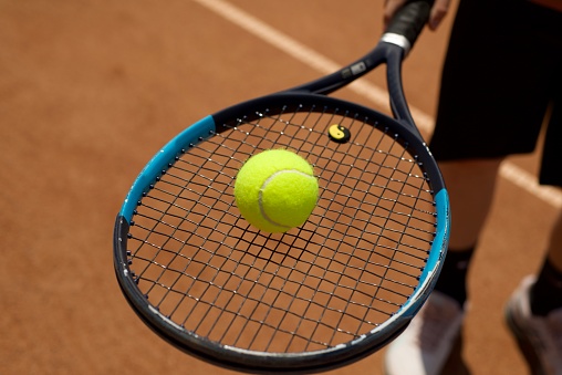 Tennis yellow ball on a racket. Tennis. Sport. Ground courts.