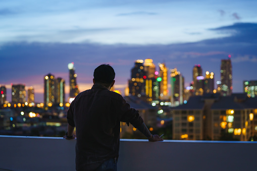 Silhouette of a man on a rooftop in the city lights.