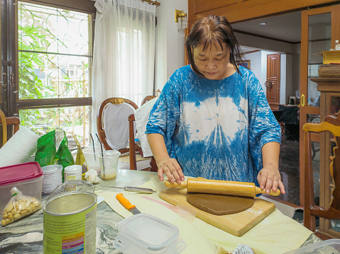 Asian senior women baking cookies in kitchen at home, Mature women making ginger bread cookie