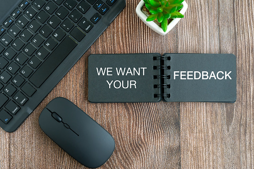 We want your feed back text on note pad on top of office desk flat lay