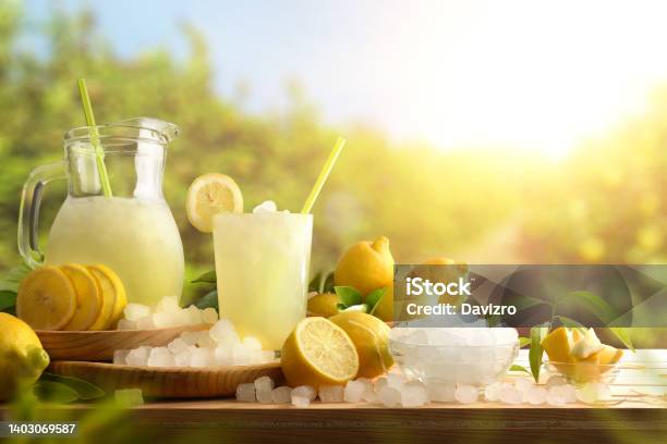 Lemonade With Ice On Table With Lemon Trees In Background Stock Photo - Download Image Now