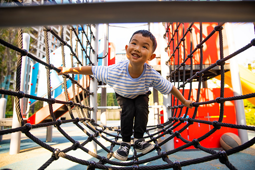 Little boy climbing rope trail