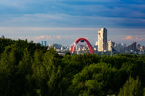 Moscow, Russia - June 12, 2022. Panoramic view of the Moscow sports center. Red metal bridge across the Moscow river. Horizontal orientation.