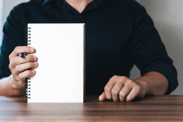 istock Businessman displays a notebook with a copy area with pen. 1403072780