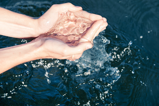 Persona que toma agua cruda de un lago con las manos photo
