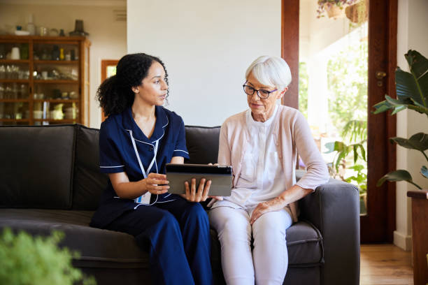 istock Home healthcare worker and a senior woman using a tablet on a sofa 1403073932
