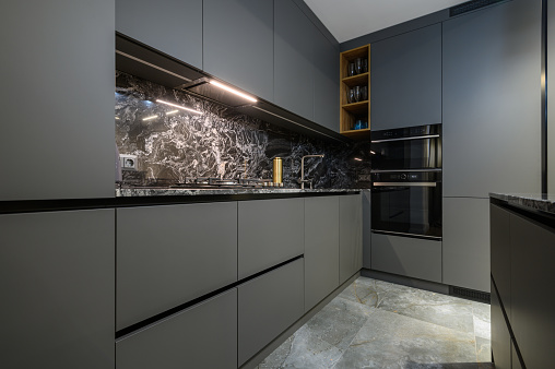 Corner view closeup to grey luxury kitchen in studio apartment interior