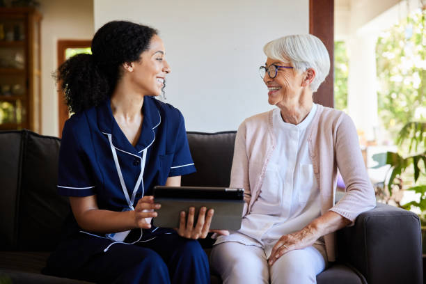 istock Senior woman and a home healthcare worker laughing while using a tablet 1403073968