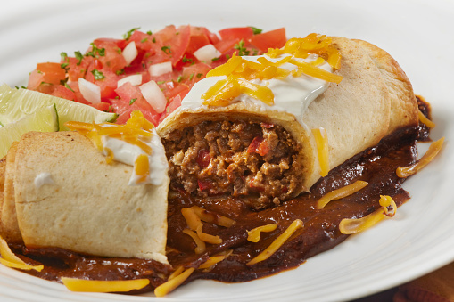 Baked Beef  Burrito with Red Peppers, Onions, Cheddar Cheese Sour Cream, Pico de Gallo and Mole Sauce