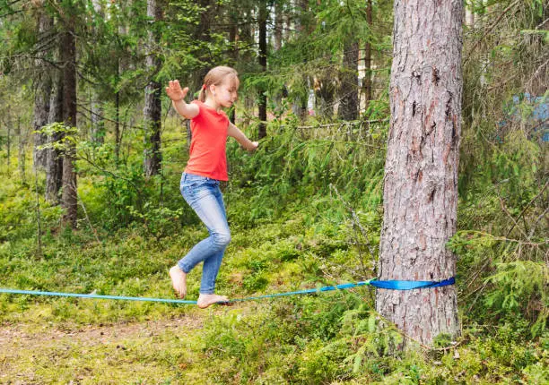 Tween girl balancing on slackline during summer holidays