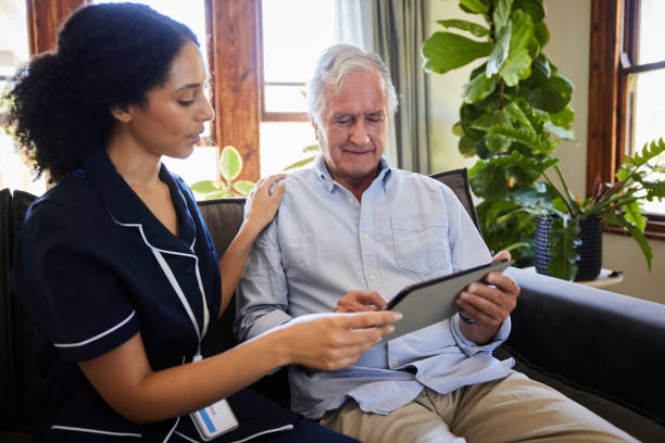 istock Home healthcare worker and a senior man using a tablet on a sofa 1403074202