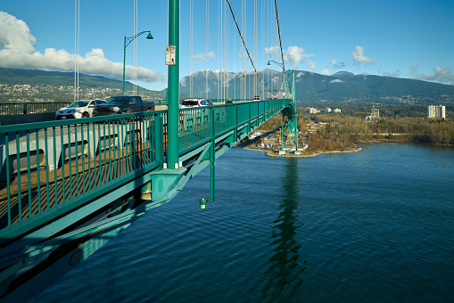 Vehicle and bicycle traffic across the Lion’s Gate Bridge in the sun.